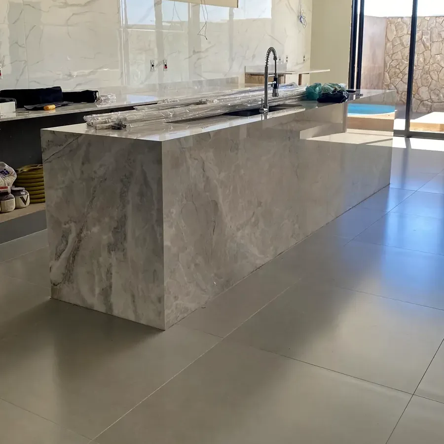 Ilha da cozinha revestida em pedra clara sobre porcelanato de grande formato
