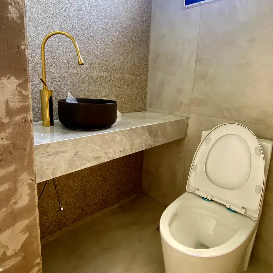 Lavabo com bancada em pedra, cuba escura e torneira dourada