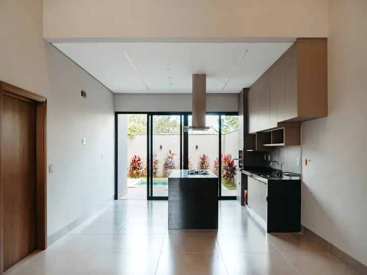 Sala e cozinha integradas com ilha escura e porcelanato claro